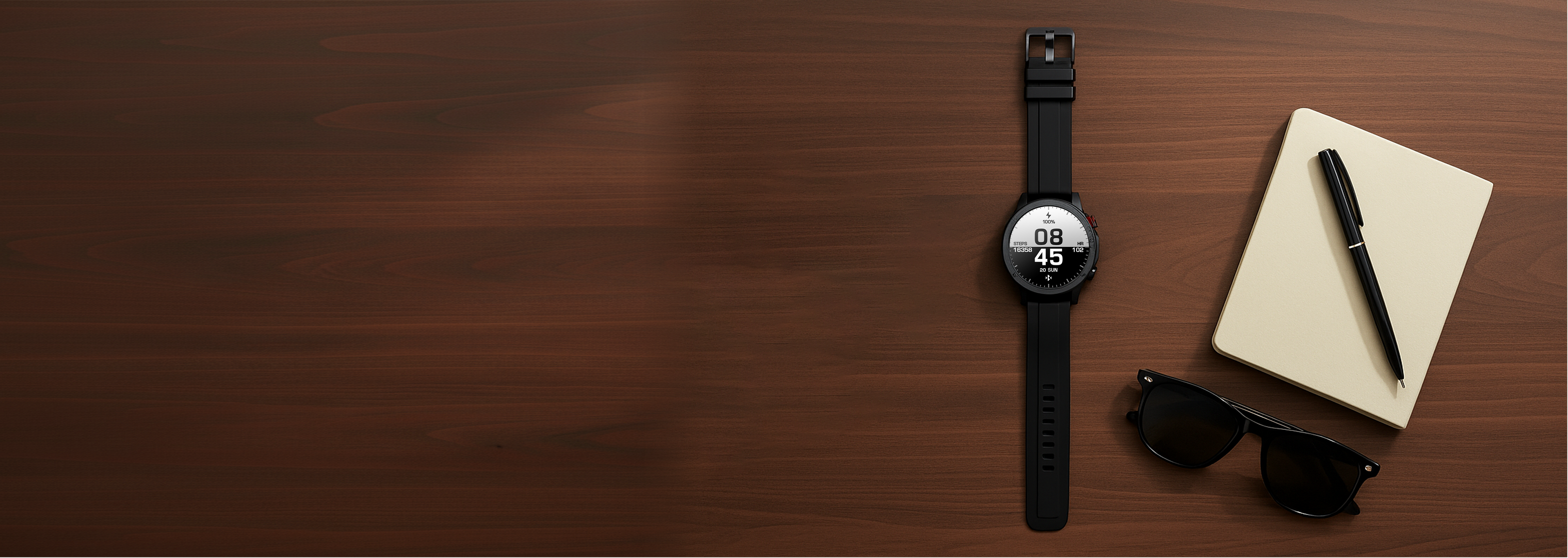 Black smartwatch on a wooden surface with sunglasses and a notebook.